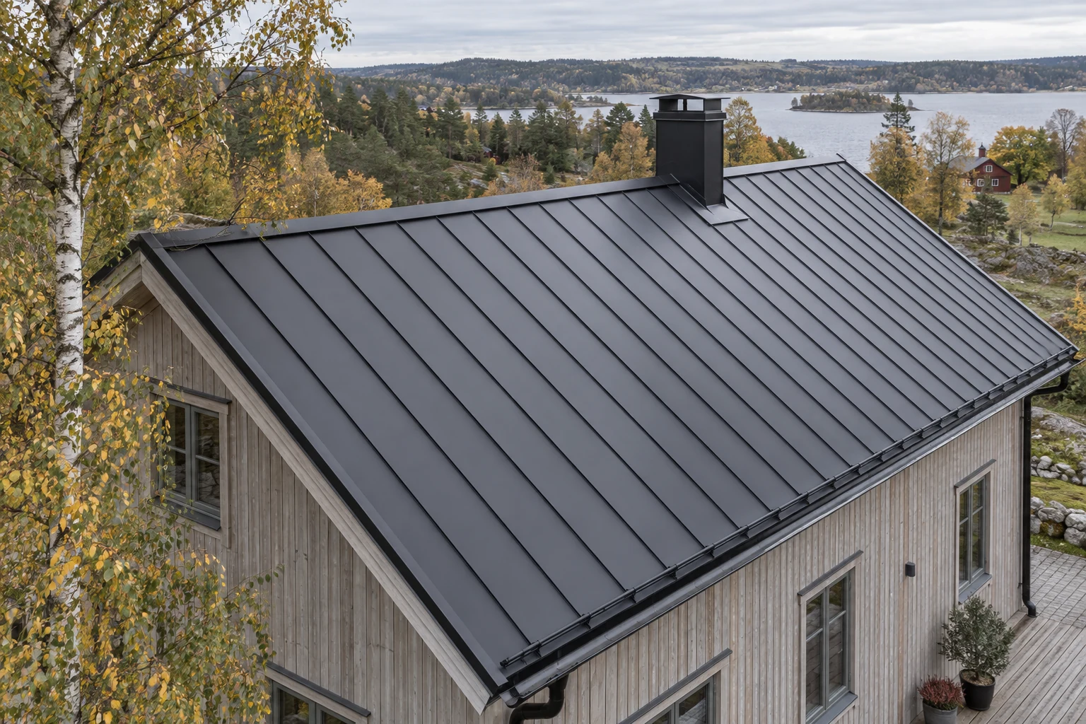 Ett sadeltak med mörk falsad plåt, skorstensbeslag och takavvattning på ett svenskt trähus